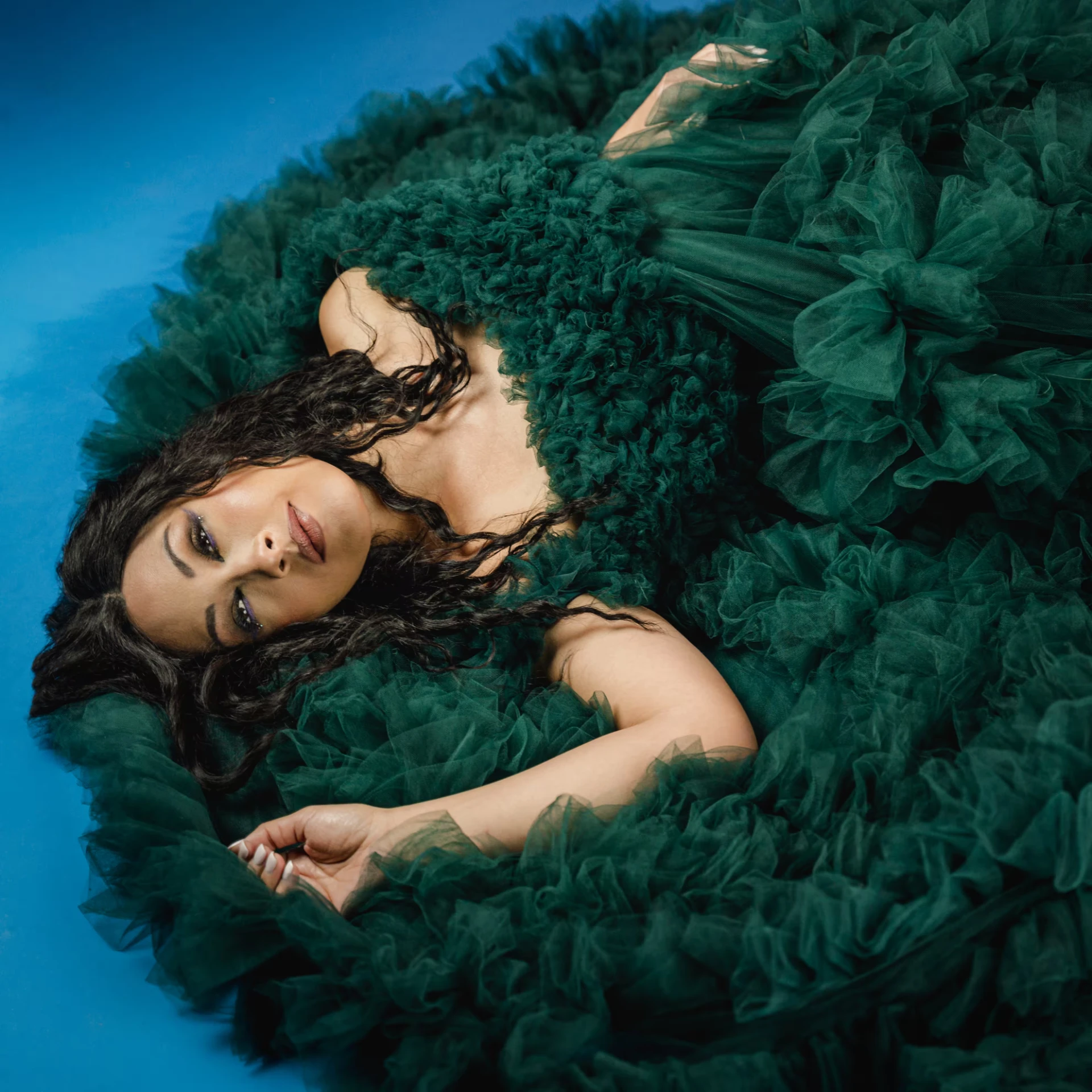 Melina Soochan reclining in an emerald gown viewed from above